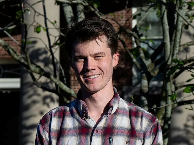 David Ween, young man with short brown hair smiling in a plaid shirt outdoors.