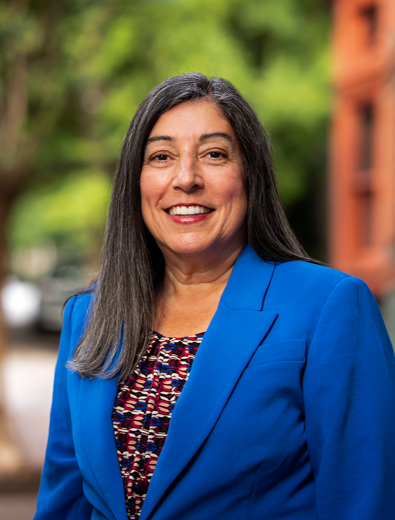 Dr. Deb Houry in a blue blazer and patterned shirt smiles at the camera.
