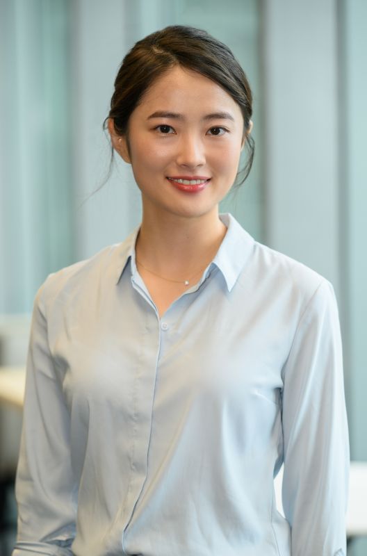 Young Asian woman in a light blue collared shirt smiles.