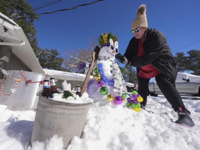 woman decorating a mardi gras themed snowman