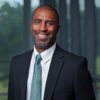 Portrait of a smiling Black man in a suit and tie.