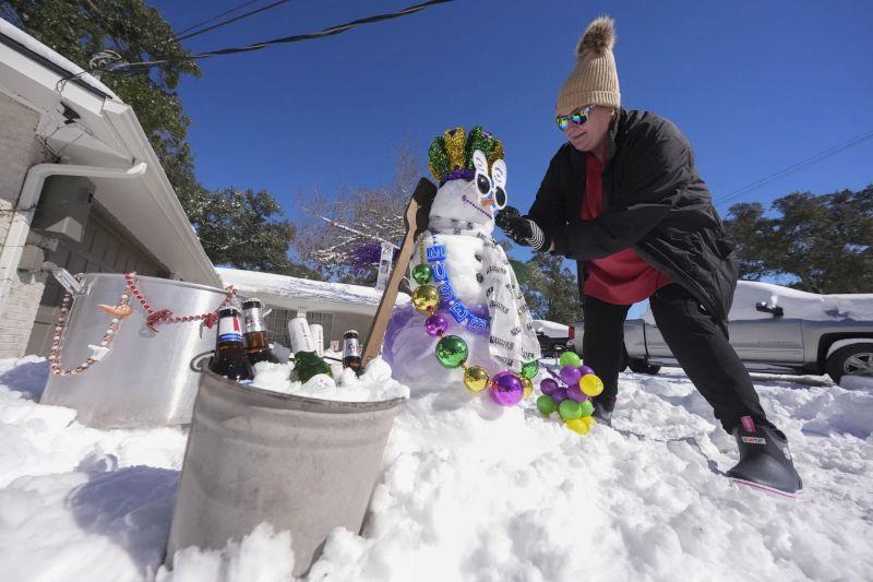 woman decorating a mardi gras themed snowman