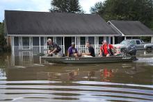 ichard Schafer navigates a boat past a flooded home in Baton Rouge on Aug. 15, 2016
