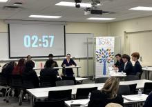 Students compete at an Ethics Bowl in a classroom with a timer showing 02:57.