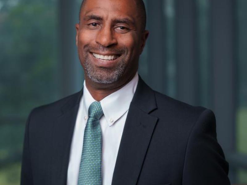 Portrait of a smiling Black man in a suit and tie.